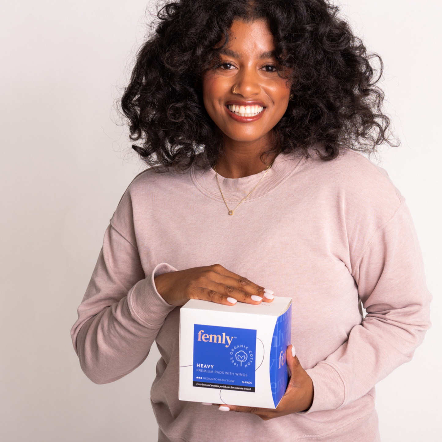 Black woman holding femly's 100% organic cotton heavy menstrual pads.